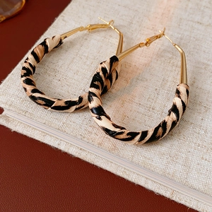 Detailed view of leopard print wrapped gold hoop earrings on a textured lifestyle background