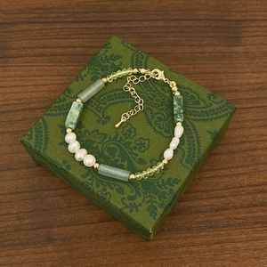 Macro detail of natural green stone and pearl beaded necklace on a vintage jewelry box