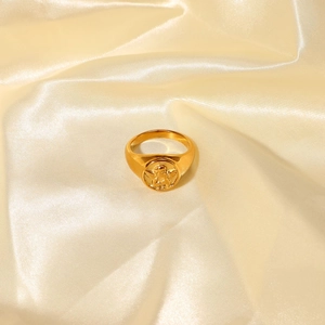 Detail of vintage 18k gold plated titanium ring with angel relief on silk background