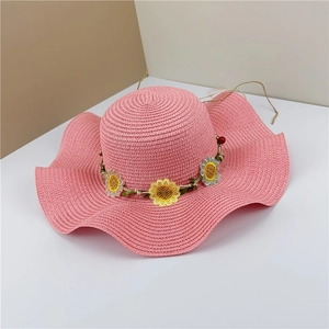 Détail du chapeau de paille rose avec broderie tournesol et bord ondulé tissé