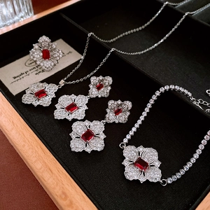 Detailed view of silver flower jewelry set with red gemstones and zircon diamonds