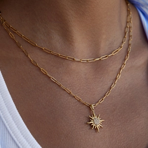 Primo piano della collana a doppia catena a graffetta dorata con ciondolo a girasole