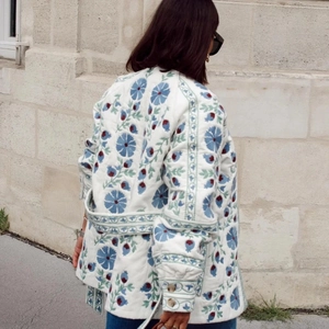 Detail view of the quilted cotton jacket featuring floral embroidery and matching waist tie