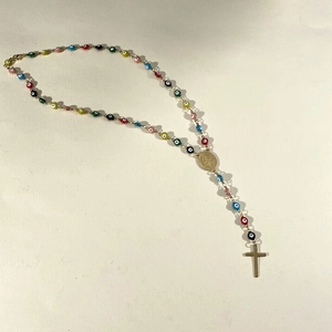 Detail of colorful Evil Eye beads with golden crucifix pendant and religious medallion