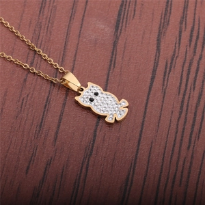 Detail of owl pendant with white and black rhinestones on a gold chain over wood