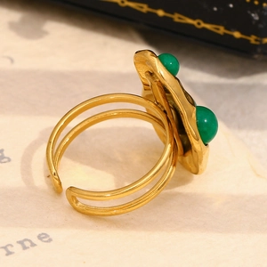 Macro detail of 18K gold-plated hammered ring with dual green bead accents and open band