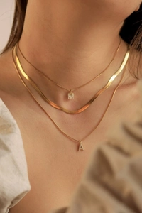 Layered gold necklaces with letter M and A pendants and a chic snake bone chain