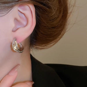 Close-up of silver interwoven clip-on earrings worn by a model in professional attire