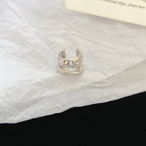 Silver double-layer ear cuff with textured metal and sparkling crystals on white paper