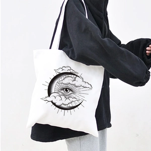 Detail of white canvas tote bag featuring mystic moon and eye print worn by a model