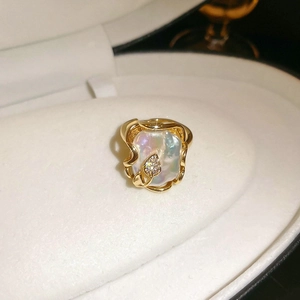 Macro d'une bague en perle baroque dorée avec feuilles en diamant dans un écrin