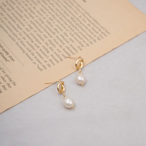 Vintage gold knot earrings with freshwater pearl drops on retro book page backdrop