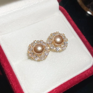 Close-up of champagne pearl earrings with bow detail and zircon halo on velvet