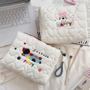 Detail of white quilted puppy makeup bag with colorful cartoon embroidery and zip closure