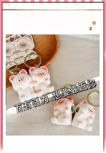 Close-up of cat couple keychains in white resin with golden rings and wooden decor