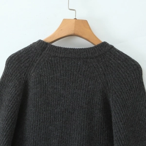 Detail of dark grey knit sweater showing crew neck and raglan sleeve texture