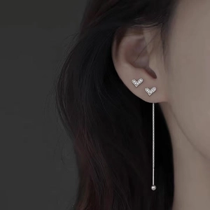Dettaglio degli orecchini a cuore in argento S925 e lunga linea di perle su un modello