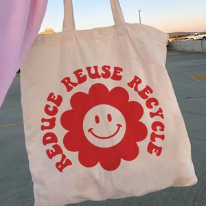 Beige canvas tote bag with red floral smile print and Reduce Reuse Recycle slogan