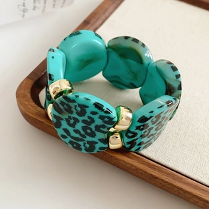 Detail shot of turquoise leopard print resin beads with gold metal spacers on a bracelet