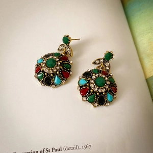 Close-up of vintage gold earrings with colorful rhinestones on an antique book page