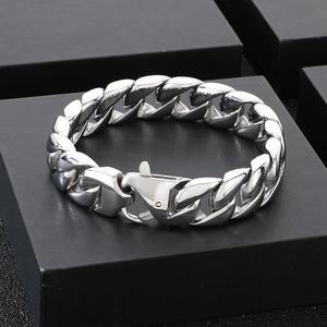 Polished silver stainless steel Cuban link bracelet with lobster clasp on a black stand