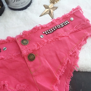 Detailansicht der pinkfarbenen Denim-Shorts mit Strasssteinen und ausgefranstem Saum
