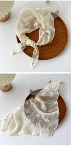 Detail showing beige triangle scarf with delicate floral embroidery and lace edges