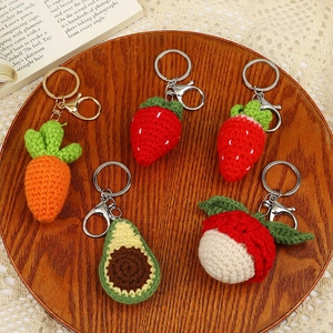 Set of 5 handmade crochet fruit keychains including strawberry and avocado on a wooden tray