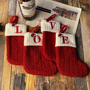 Close-up of LOVE embroidered red cable-knit Christmas stockings on wooden surface