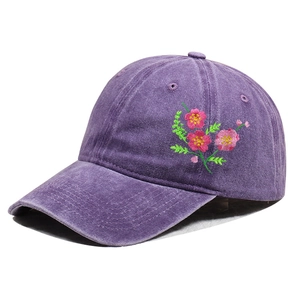 Detail of floral embroidery on purple washed cotton baseball cap with vintage texture