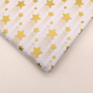 Macro shot of white tissue paper featuring decorative gold star patterns for flower wrapping