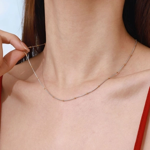 Minimalist 18k silver steel necklace with gold beads worn on neck for a modern look