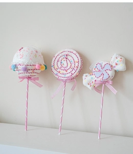 Detail of pink and white plush peppermint candy ornaments with glitter and velvet bows