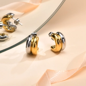 Detail of two-tone C-shape stainless steel earrings with gold and silver finish