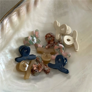Collection of colorful mini acetate hair claws in a pearlescent shell tray