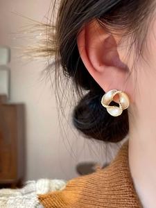 Detail of 14K gold plated spiral flower earring with pearls and diamonds on a model