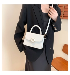 Close-up of stylish white leather handbag with golden round buckle worn by a model