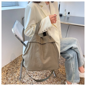 Olive green lightweight nylon tote bag shown in a stylish casual lifestyle setting