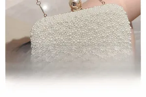 Detailed close-up of pearl evening clutch bag with gold chain and large pearl clasp