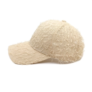 Detail of beige baseball cap featuring unique all-over distressed fringe and frayed texture