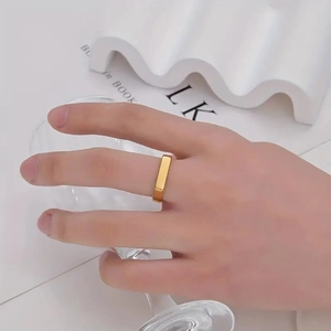 Gold plated stainless steel ring with flat rectangular geometry on a model's hand