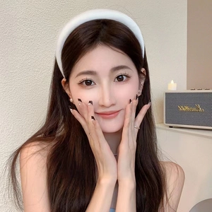 Close-up of a white wide-brimmed sponge headband worn by a model in a cozy indoor setting