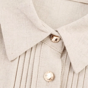 Macro view of beige linen shirt texture with golden buttons and pleated front details