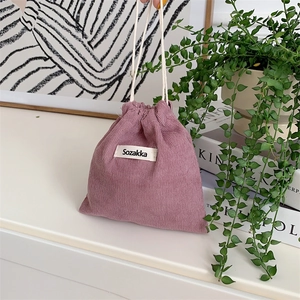Detail of pink corduroy drawstring bag showing high-quality fabric texture and brand label