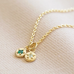 Macro shot of gold necklace with green and yellow cubic zirconia birthstone charms