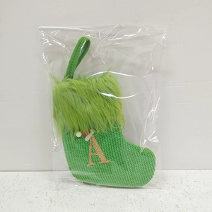 Green knit Christmas stocking with faux fur trim and gold glitter letter A in packaging