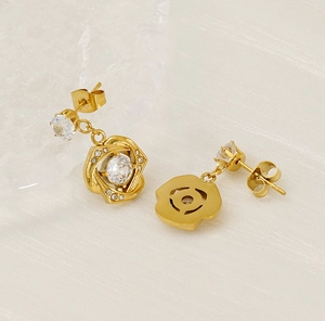 Close-up of golden cross earrings featuring zircon stones and intricate flower twists