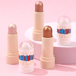 Drei metallische Highlighter-Sticks in Champagner, Gold und Bronze auf lila Bühnen-Podest