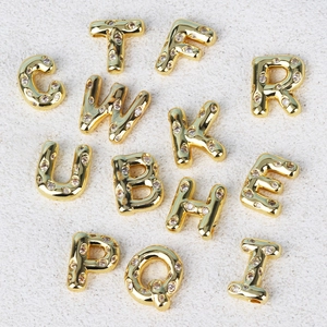 Detail view of gold alphabetic pendants inlaid with sparkling clear cubic zirconia