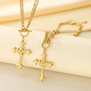 Detail of gold double-layer cross necklace and bracelet set on smooth silk background